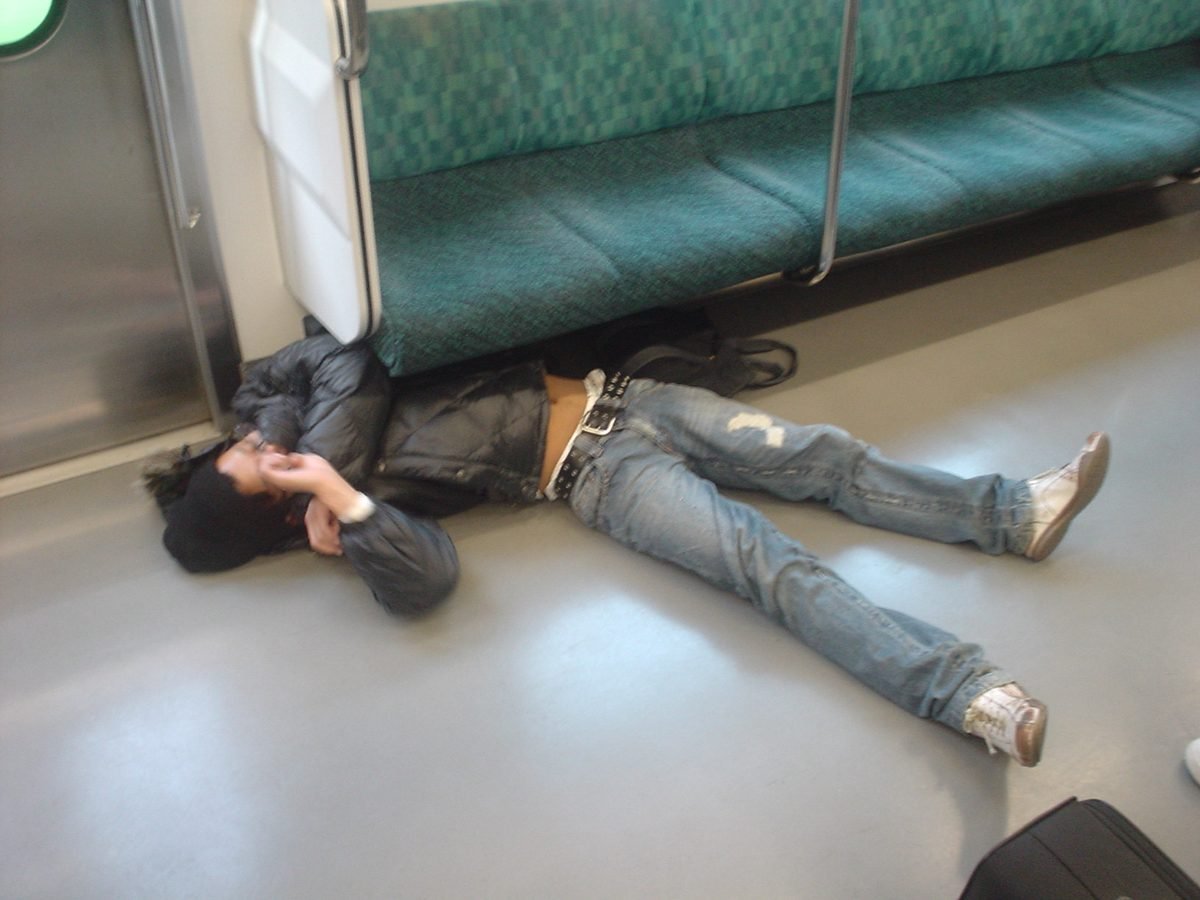 A passenger asleep on the floor of a train carriage in Japan