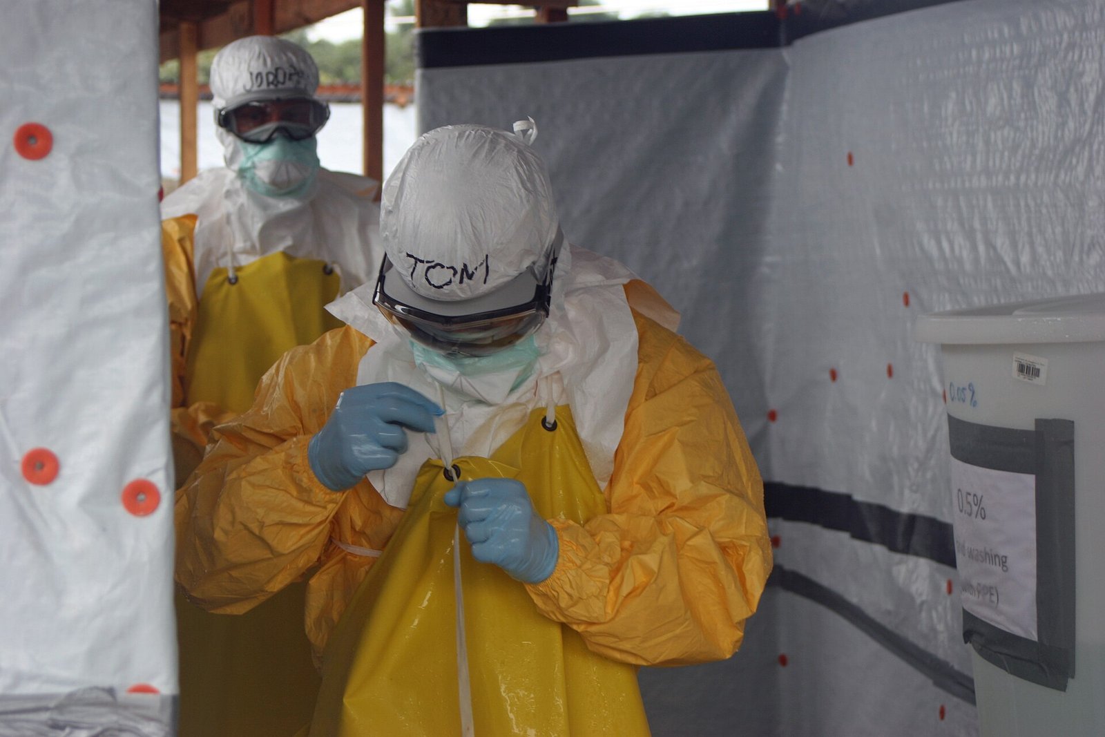 Health worker in a yellow protective suit, goggles and mask leaving an Ebola treatment unit