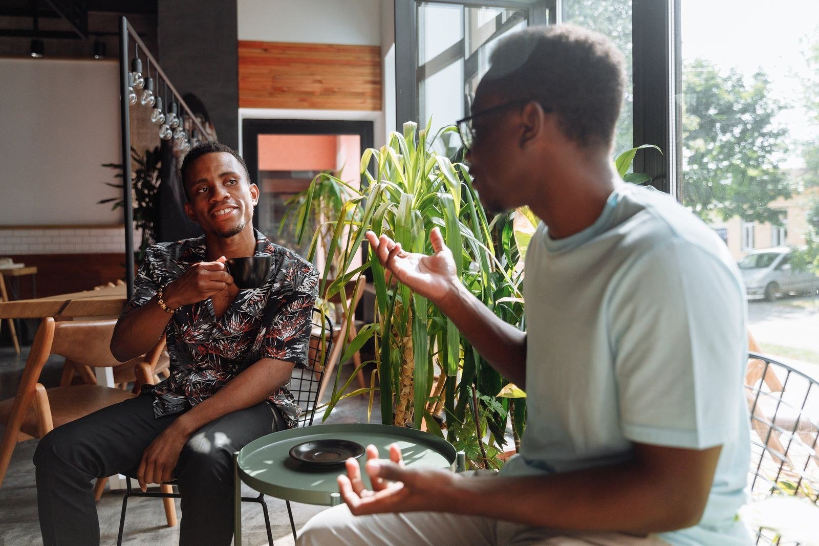 Two friends talking over coffee by a cafe window