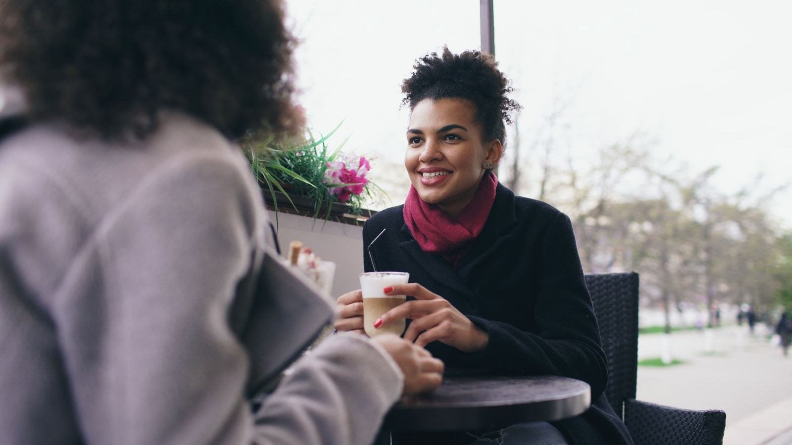 Two women chatting over coffee at an outdoor cafe